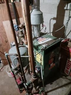 Responded to service call for non-functioning New Yorker boiler system. Inspected the aging green boiler unit and associated piping connections in basement mechanical room. Examined expansion tank, multiple valves, and copper piping network; performed necessary repairs to restore proper system operation.