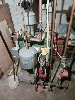 Responded to service call for non-functioning New Yorker boiler system. Inspected the aging green boiler unit and associated piping connections in basement mechanical room. Examined expansion tank, multiple valves, and copper piping network; performed necessary repairs to restore proper system operation.