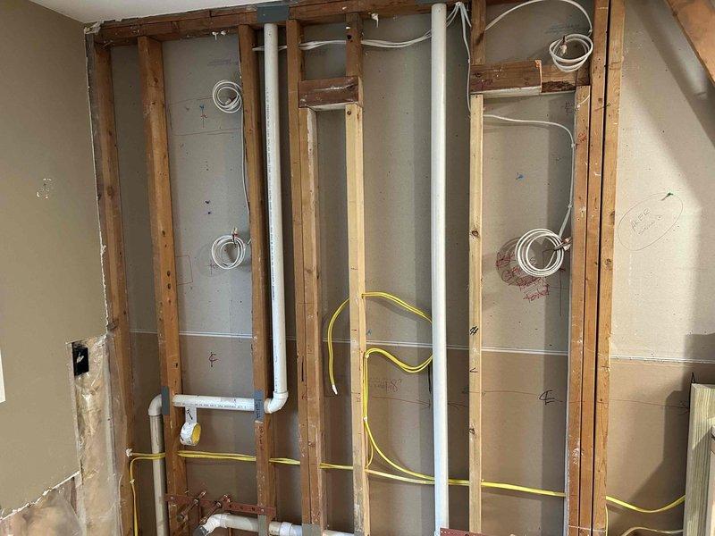 Completed rough-in electrical installation for bathroom remodel, including running new wiring through wall framing for fixtures and outlets. Installed electrical boxes and routed yellow and white cables through studs according to code requirements, coordinating placement with plumbing infrastructure prior to drywall completion.