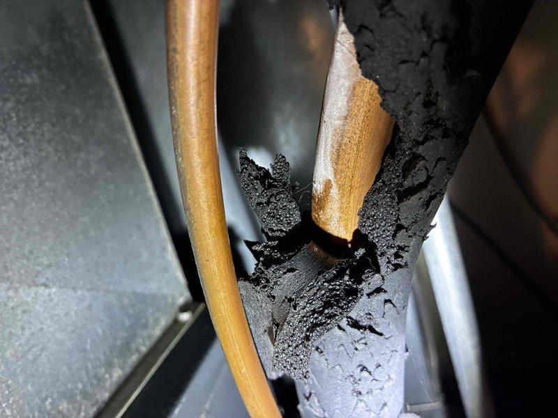 Responded to no cooling complaint on 10+ year old HVAC system. Upon inspection, found severely deteriorated refrigerant line insulation with extensive damage and exposure of copper piping at air handler penetration point. Insulation material showed significant age-related degradation with crumbling foam and missing sections throughout. Restored system to operational cooling status and performed complete maintenance tune-up including filter replacement, coil cleaning, and system performance verification. All refrigerant lines properly re-insulated to prevent condensation and maintain energy efficiency. System tested and confirmed operating within manufacturer specifications upon completion.