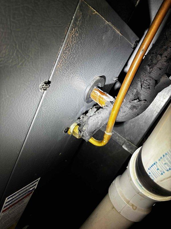 Responded to no cooling complaint on 10+ year old HVAC system. Upon inspection, found severely deteriorated refrigerant line insulation with extensive damage and exposure of copper piping at air handler penetration point. Insulation material showed significant age-related degradation with crumbling foam and missing sections throughout. Restored system to operational cooling status and performed complete maintenance tune-up including filter replacement, coil cleaning, and system performance verification. All refrigerant lines properly re-insulated to prevent condensation and maintain energy efficiency. System tested and confirmed operating within manufacturer specifications upon completion.