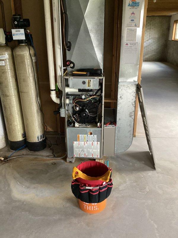 Completed prepaid AC clean and check maintenance visit on residential system located in basement utility area. Performed standard inspection of furnace and air conditioning components with access panels opened to examine blower motor, wiring, and internal mechanical systems. During refrigerant charge assessment, identified system is low on charge and documented findings for customer discussion regarding necessary refrigerant recharge service.