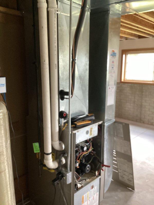 Completed prepaid AC clean and check maintenance visit on residential system located in basement utility area. Performed standard inspection of furnace and air conditioning components with access panels opened to examine blower motor, wiring, and internal mechanical systems. During refrigerant charge assessment, identified system is low on charge and documented findings for customer discussion regarding necessary refrigerant recharge service.
