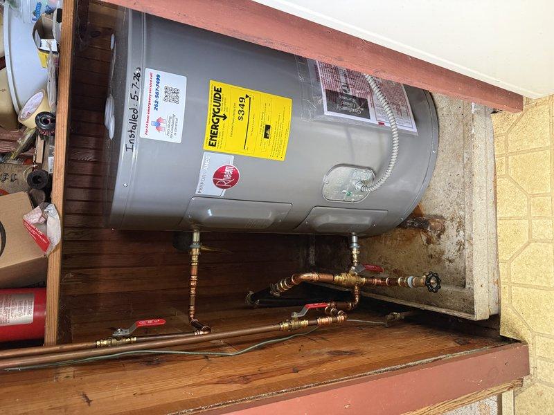 Completed installation of a 30-gallon Rheem electric water heater in a residential utility space. Removed existing unit and installed new water heater on wooden platform, connecting copper supply lines with brass ball valves and fittings. Installed flexible metallic conduit for electrical connection, verified all plumbing connections for proper seal and operation, and ensured compliance with manufacturer specifications and local code requirements.