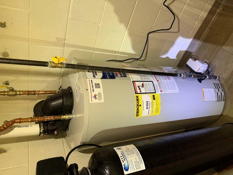 Completed warranty water heater replacement in utility room. Removed and replaced defective unit with new water heater, reconnecting all copper supply lines, brass fittings, and gas shut-off valve. Cut off manufacturer label from old unit for warranty claim documentation and filing purposes. Verified all plumbing connections, tested system operation, and confirmed proper function of associated components including circulation pump and pressure tank.