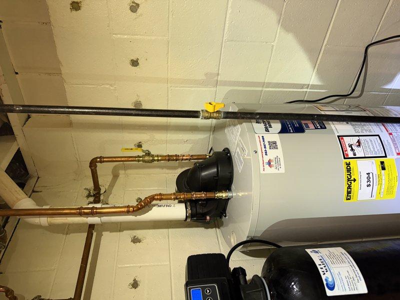 Completed warranty water heater replacement in utility room. Removed and replaced defective unit with new water heater, reconnecting all copper supply lines, brass fittings, and gas shut-off valve. Cut off manufacturer label from old unit for warranty claim documentation and filing purposes. Verified all plumbing connections, tested system operation, and confirmed proper function of associated components including circulation pump and pressure tank.