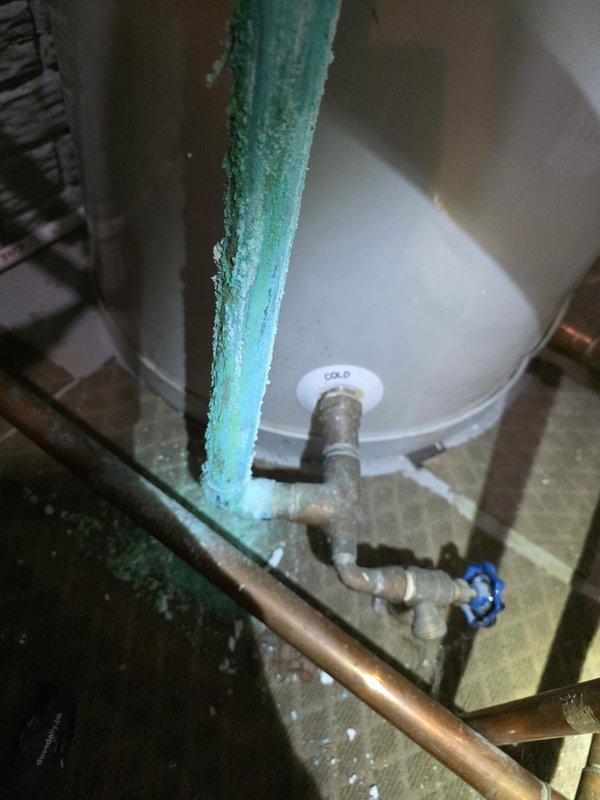 Responded to emergency service call for leaking copper pipe with severe corrosion. Upon arrival, found vertical copper cold water supply line completely covered in thick turquoise-green corrosion and actively leaking. Replaced deteriorated copper piping connected to water heater system. Installation included new copper pipe, brass fittings, and proper connections to existing SuperStor water heater and associated plumbing components including circulator pump and expansion tank.