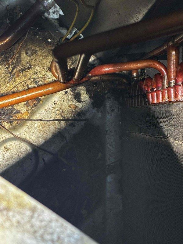 Performed comprehensive leak test on non-operational air conditioning system and identified leak in exterior evaporator coil. The coil exhibited significant dirt and debris accumulation between fins, with heavy grime buildup affecting overall system performance. Documented equipment condition with photographs showing the failed coil assembly and surrounding mechanical components in crawlspace area. Provided customer with detailed estimate for complete coil replacement to restore cooling functionality.