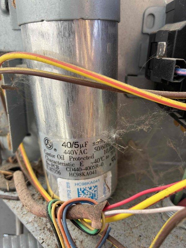 # HVAC Service Call - No Cooling Condition

Responded to a no cooling complaint on a residential air conditioning system over 10 years old. Upon arrival, performed diagnostic evaluation of the outdoor condensing unit located in the side yard. Inspected the condenser unit which showed signs of age and lack of recent maintenance, with visible dust accumulation and spider webs present in the electrical compartment.

Accessed the electrical control panel and identified a failed dual-run capacitor rated at 40/5µF, 440VAC. The capacitor showed signs of deterioration and was determined to be the root cause of the no cooling condition, preventing the compressor and condenser fan motor from operating properly. 

Removed the defective capacitor and replaced it with a new dual-run capacitor meeting the manufacturer's specifications. Reconnected all electrical wiring to proper terminals, ensuring secure connections on both the compressor (HERM) and fan motor (FAN) circuits. Verified proper wire ro