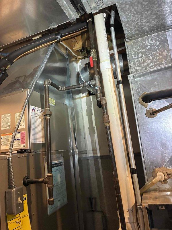Responded to service call for water accumulation on top of furnace unit below evaporator coil. Upon inspection, identified active water leak condition requiring immediate system shutdown to prevent further damage to equipment and surrounding area. Advised customer to power down system and verified electrical disconnects at breaker panel. Documented existing HVAC installation including furnace/air handler unit, copper refrigerant lines, gas piping, PVC condensate drainage system, and ductwork configuration for follow-up repair assessment.