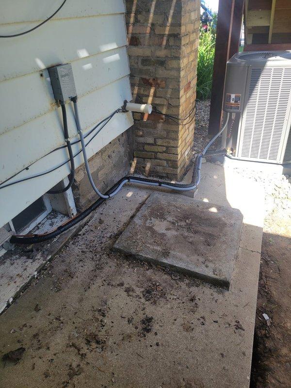 Completed full air conditioning system and evaporator coil replacement at residential property. Removed existing outdoor condensing unit and indoor evaporator coil, installing new equipment with 15-foot refrigerant line set and "B" width coil configuration. Relocated outdoor unit to right side of property on new concrete pad with rock base for improved placement and accessibility. Replaced electrical disconnect with new Cutler Hammer panel, installing 30-amp circuit for air conditioning unit and verifying 15-amp furnace circuit. Navigated existing humidifier installation during indoor coil replacement, working around basement mechanical room constraints including water heater, water softener, and pressure tank. Routed copper refrigerant lines around existing brick chimney structure with proper insulation. Connected all electrical conduits and refrigerant lines, performed vacuum and refrigerant charge procedures, and tested system operation to verify proper cooling performance and elect