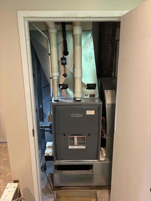 Responded to service call for leaking indoor evaporator coil. Upon inspection, confirmed active refrigerant leak at indoor coil assembly located in utility closet. Documented equipment condition and leak evidence with photographs showing furnace installation and associated ductwork. Contacted property caretaker prior to arrival as requested to coordinate access and discuss findings.