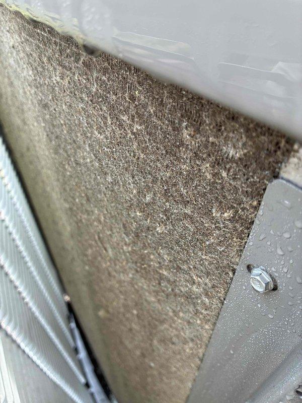 Completed prepaid maintenance visit on air conditioning system. Inspected evaporator coil assembly and found significant dust and debris accumulation on filter media and coil fins, with visible dirt buildup affecting airflow efficiency. Documented moisture present on coil surfaces indicating active condensation during operation. Photographed heavily contaminated air filter showing matted fibrous material and particulate matter throughout filtering surface. Observed dirt streaking across evaporator coil fins, particularly concentrated in center sections, while some areas remained cleaner. System operational at time of inspection with condensation visible on housing components. Customer enrolled in annual quality plan providing parts and filter discount benefits.