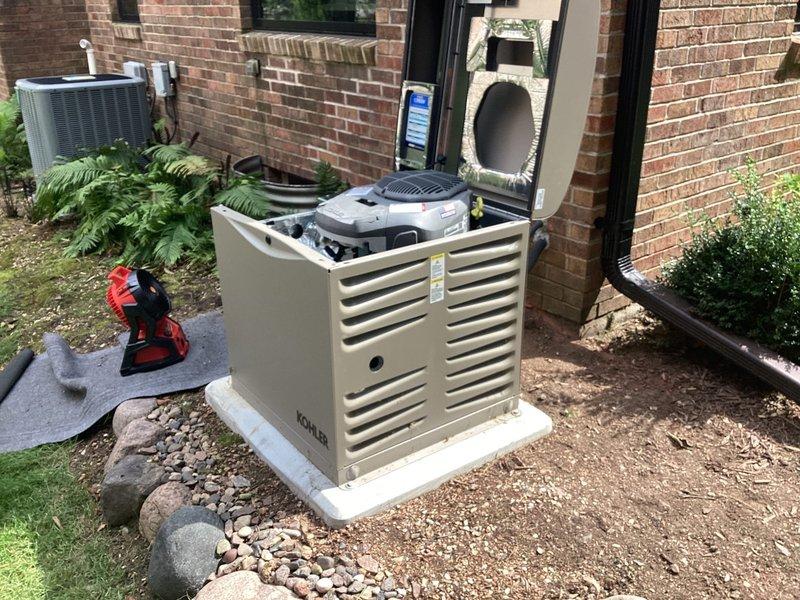 Installed Kohler model 12RESV 12KW air-cooled home standby generator with steel cabinet on pre-set concrete pad at corner of residence. Installed 100A 16-space automatic transfer switch adjacent to existing Bryant main electrical panel, with homeowner-selected circuits for backup power coverage. Ran approximately 35 feet of 1-inch natural gas line through open basement from opposite side where gas main enters, tying in ahead of existing furnace and water heater to supply generator fuel source. Completed all necessary line and low voltage wiring connections between generator, transfer switch, and main panel. Installed exterior natural gas piping with proper fittings and painted gas line gray with oil-based paint per specification. Generator package included battery and carburetor heater for cold weather operation. Verified proper operation of automatic transfer switch functionality and generator startup sequence. System tested and left fully operational with 10-year labor warranty and 1
