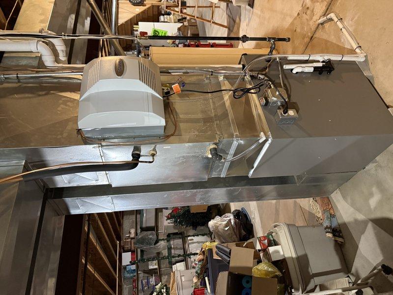 Successfully completed installation of EL297V 97% AFUE two-stage variable speed upflow furnace with 70,000 BTU capacity in basement location. Integrated Ecobee smart thermostat for enhanced climate control and energy management. Installed AA 700 bypass-style humidifier unit with cylindrical water reservoir mounted directly to supply ductwork with proper electrical connections and water supply lines. Addressed existing 4-inch B-vent chimney configuration by removing obsolete vent fitting in basement to accommodate new high-efficiency condensing furnace venting requirements. All ductwork connections secured with proper strapping and supports to ceiling joists. System tested and operational upon completion with all components functioning within manufacturer specifications.