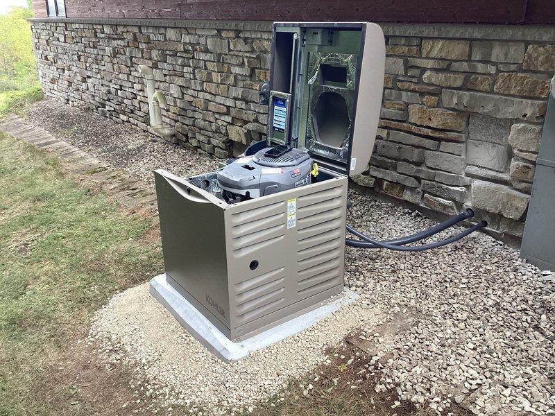 Installed Kohler 12RESV 12KW air-cooled home standby generator with steel cabinet on concrete pad adjacent to existing AC unit on side of residence. Mounted 100-amp, 16-space automatic transfer switch next to main electrical panel to provide backup power to owner-selected circuits during outages. Completed all line voltage and low-voltage wiring connections between generator, transfer switch, and electrical panel per manufacturer specifications. Installed battery and carburetor heater for cold weather operation.

Relocated three small evergreen shrubs from installation area to accommodate generator placement. Ran natural gas supply line from existing gas meter to generator, including all necessary pipe, fittings, and connections for fuel supply. Painted exterior gas piping gray using oil-based paint for corrosion protection and aesthetic finish. Verified proper gas pressure and flow to unit.

Tested automatic transfer switch operation and confirmed seamless transition between utility a