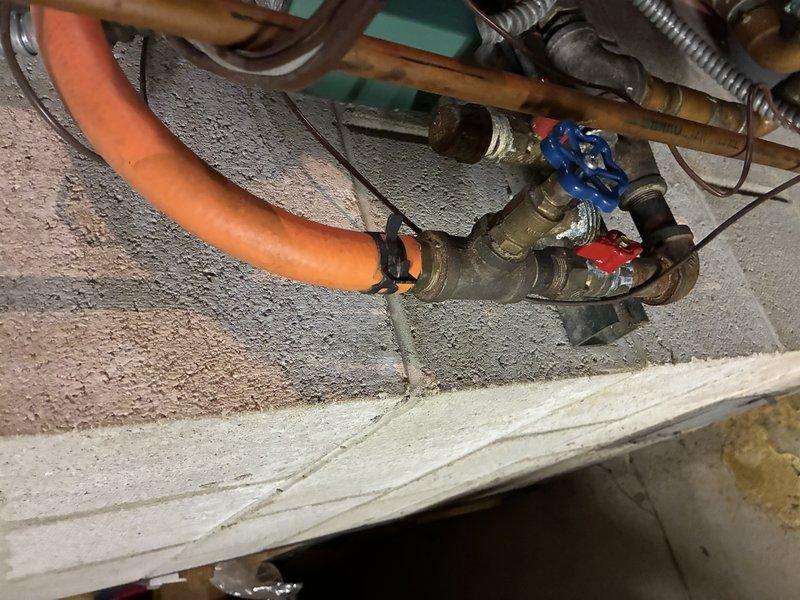 Responded to service call for leaking Burnham indirect-fired water heater connected to boiler system. Upon inspection, confirmed active leak at water heater unit and identified additional plumbing components requiring attention, including deteriorated piping connections and compromised valve assemblies beneath ceiling-mounted infrastructure. Documented equipment conditions through photography, noting moisture damage to surrounding areas and age-related deterioration of brass fittings and gate valves. Prepared comprehensive quote for water heater replacement and necessary ancillary repairs to restore system integrity.