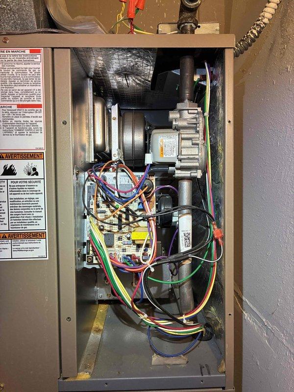 Responded to no heat call on aging HVAC system. Upon inspection, accessed main cabinet and evaluated blower motor assembly, electrical connections, and control board components. Documented system configuration showing multiple warning labels and organized wire bundles throughout compartment. Examined control component with part number 10081, noting proper terminal connections and wire routing from unit. All electrical connections were secure with no loose terminals observed. System components appeared functional with proper mounting and organized wiring harnesses maintained throughout cabinet. Blower motor assembly and ductwork connections were intact with no visible damage to mechanical components.