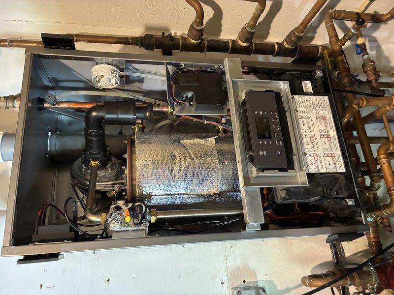 Responded to emergency service call for boiler system displaying fault code 101 related to indirect water heater malfunction. Performed diagnostic inspection of heating system, including examination of three-way valve operation and boiler components. Documented existing piping configuration, pump assembly, and control panel conditions through photographic evidence. Contacted technical support to confirm diagnosis and ordered necessary replacement parts. System evaluation indicates potential pump failure as primary cause of recurring shutdown issues, requiring part arrival before repair completion can proceed.