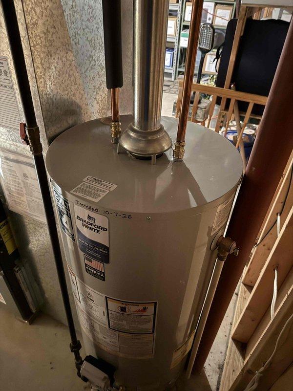 Completed installation of a 40-gallon Bradford White power vent water heater in residential basement utility area. Removed existing water heater and installed new unit with proper copper piping connections, brass fittings, and power vent flue system. All plumbing connections were secured, system was tested for proper operation, and payment was collected upon completion.