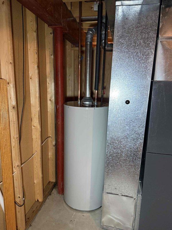 Completed installation of a 40-gallon Bradford White power vent water heater in residential basement utility area. Removed existing water heater and installed new unit with proper copper piping connections, brass fittings, and power vent flue system. All plumbing connections were secured, system was tested for proper operation, and payment was collected upon completion.