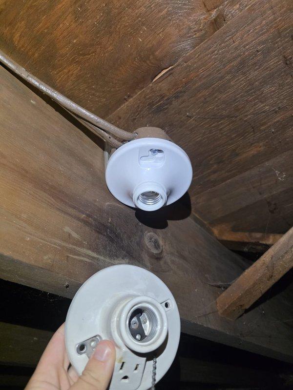 Removed two defective ceiling light fixtures (one flickering, one inoperative) from the basement joists and installed replacement porcelain-style lampholders, securing each to the framing and terminating the supply conductors at the fixture base. Verified proper operation of the new fixtures with lamps installed, restoring full basement lighting.