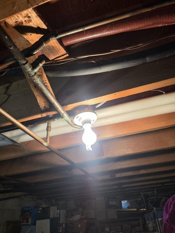 Removed two defective ceiling light fixtures (one flickering, one inoperative) from the basement joists and installed replacement porcelain-style lampholders, securing each to the framing and terminating the supply conductors at the fixture base. Verified proper operation of the new fixtures with lamps installed, restoring full basement lighting.