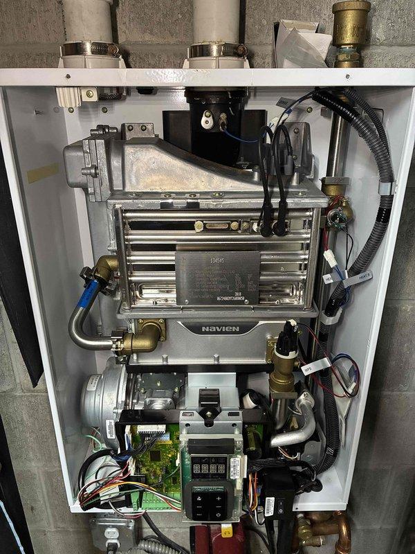 Performed prepaid annual maintenance on the wall-mounted Navien tankless boiler, opening the unit and visually inspecting the stainless steel heat exchanger, venting, piping, fan/blower assembly, and control board. All components were found clean and free of frost, rust, or damage. Borescope inspection was also performed on an additional coil assembly, revealing heavy fibrous buildup and discoloration on the tubes that should be addressed to maintain proper performance.