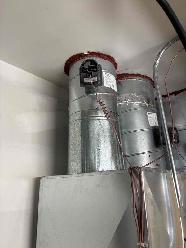 Responded to a customer complaint of uneven heating and cooling in the main residence and inspected the zoned ductwork, including the plenum, round trunk takeoffs, mastic-sealed ceiling penetrations, and damper actuator wiring. Observed the damper actuator and low-voltage control wiring to be secured and intact, with no visible air leakage, damage, or anomalies at the duct connections or conditioned space.