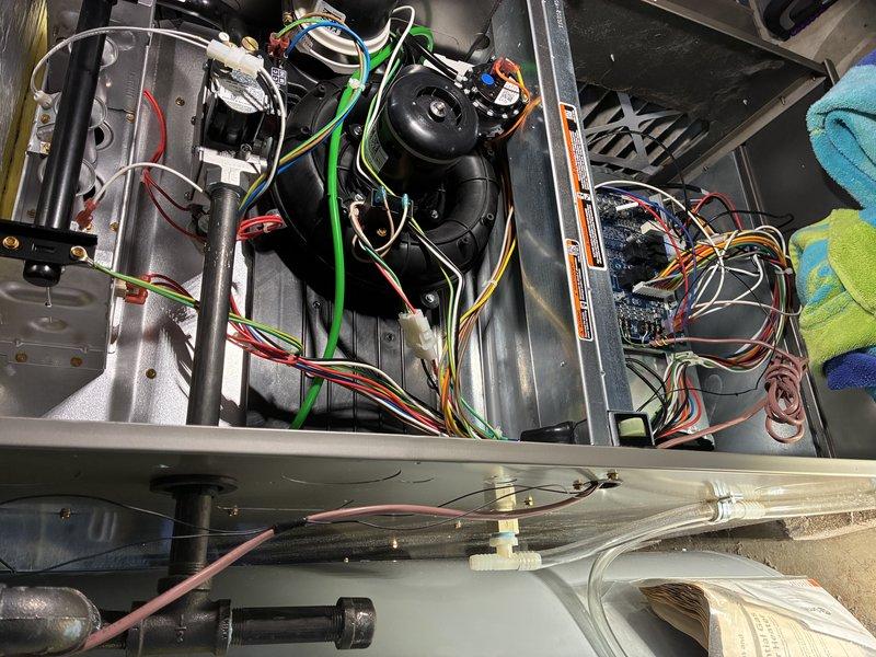 Responded to a callback for water leaking beneath the furnace and found the condensate drain hose disconnected from the condensate trap inside the furnace cabinet. Reconnected the hose to the trap, secured it with spring clamps, and tested the system to confirm proper condensate drainage with no further leaks.