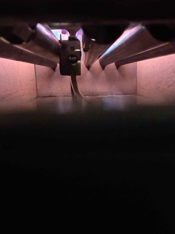 Performed annual prepaid maintenance on the boiler, inspecting the burner compartment and combustion area, including burner tubes, igniter/sensor assembly, and flame pattern, which showed normal operation upon startup. Noted significant corrosion, rust buildup, and debris on the combustion chamber floor and surrounding surfaces, along with a crack in the refractory material, and recommended further evaluation and repair to prevent further deterioration.
