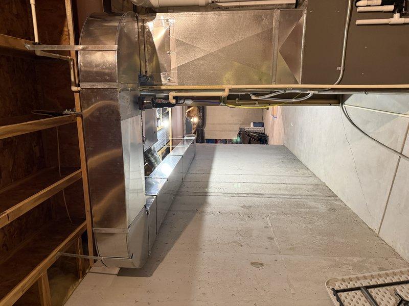 Completed the finish phase of the furnace and zoned ductwork installation following drywall completion. Removed the manual dampers from the existing supply trunks, ran a dedicated 35-ft basement supply trunk off the furnace with the required fittings, and routed the return through the staircase framing. Installed and sealed Honeywell zone damper actuators with foil-taped seams, with the system left clean and intact.