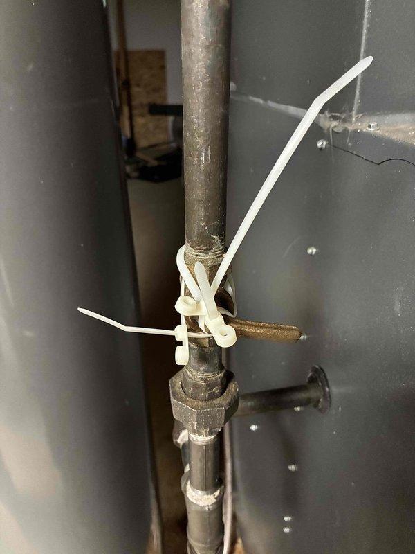 Responded to a no-heat call on a 10+ year old hydronic heating system and inspected the exterior PVC vent/intake termination, which was clear of obstructions, frost, or damage. Found the boiler supply/return piping valve with a corroded handle secured in position with zip ties, and verified valve position and operation to restore proper flow. Heating system returned to service.
