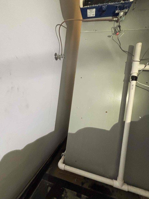 Responded to commercial HVAC water leak service call for a 6-year-old system. Diagnosed water accumulation from condensate drain line blockage in utility area, cleared obstruction in PVC drainage pipes, and verified proper system operation. Documented repair with photos showing furnace unit with exposed control panel and the drainage configuration after service completion.