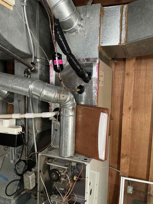 Conducted comprehensive furnace replacement estimate for aging system located in basement utility area. Evaluated existing installation which showed significant dust accumulation and wear, including central furnace unit, galvanized metal ductwork, flexible ducts, and associated control components. Documented current system configuration with photographs to support replacement recommendation, noting potential upgrades to improve efficiency and airflow distribution.