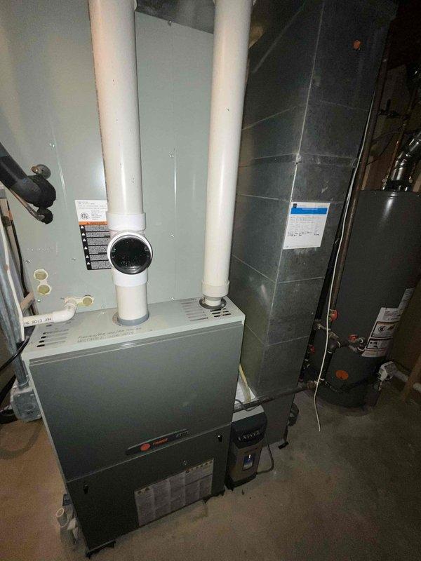 Completed BFMA tune-up on 11-year-old furnace system, which included inspection of the furnace unit with PVC exhaust/intake pipes and connected ductwork. System appears to be in good working condition with no visible damage. Also inspected the hot water heater installation with its associated plumbing components, vent pipe, and valves.