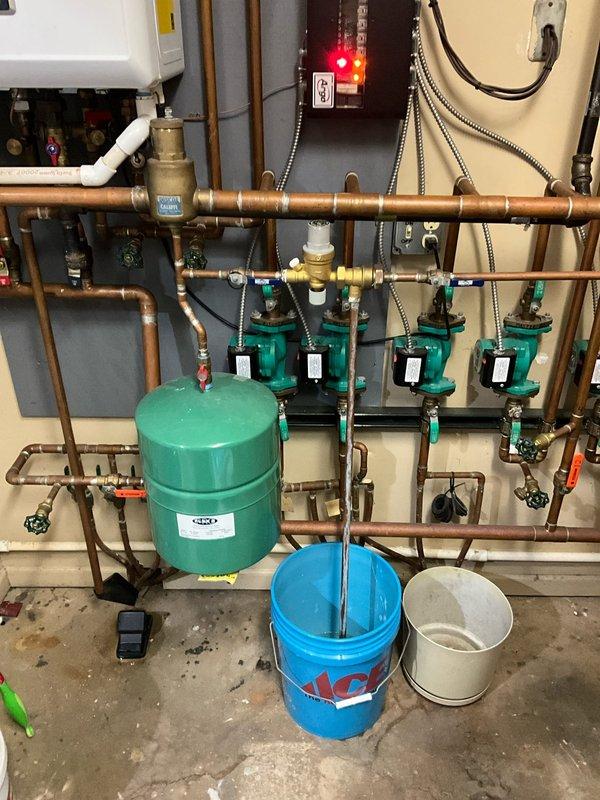 Responded to after-hours call regarding hydronic heating system issue. Inspected mechanical room with four circulation pumps showing fault indicators on control panel. Performed maintenance on expansion tank and circulation pumps, draining affected components into collection buckets, and restored system to normal operation.