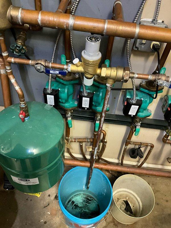 Responded to after-hours call regarding hydronic heating system issue. Inspected mechanical room with four circulation pumps showing fault indicators on control panel. Performed maintenance on expansion tank and circulation pumps, draining affected components into collection buckets, and restored system to normal operation.