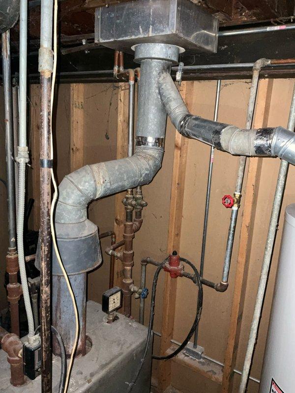 Conducted a comprehensive evaluation of an aging Bradford White water heater system located in the basement utility area. Inspection revealed significant wear on the galvanized metal ductwork, deteriorating copper water pipes with visible discoloration, and suboptimal sealing at duct connections. Recommended replacement of the complete boiler system with upgraded components to improve efficiency and address potential safety concerns with the current ventilation configuration.