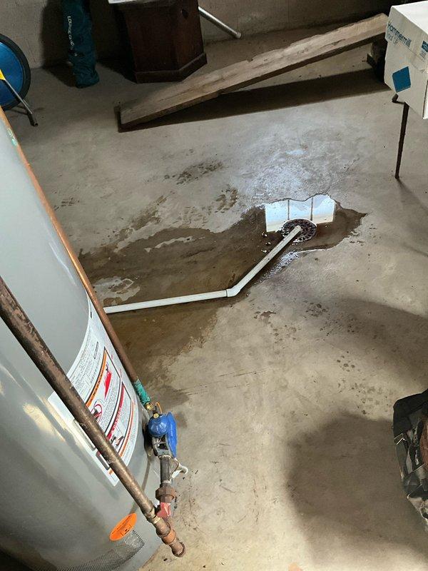 Responded to service call for leaking Rheem tanked water heater. Discovered active leak causing water pooling around basement floor drain and PVC drainage system. Replaced faulty water heater with new unit, ensuring proper connections to existing copper supply lines and ductwork, resolving the water intrusion issue.