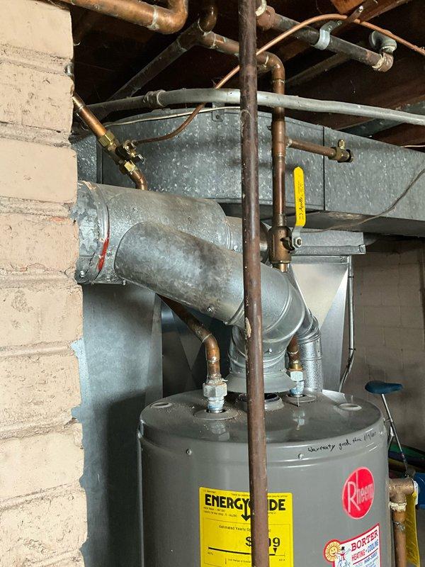 Responded to service call for leaking Rheem tanked water heater. Discovered active leak causing water pooling around basement floor drain and PVC drainage system. Replaced faulty water heater with new unit, ensuring proper connections to existing copper supply lines and ductwork, resolving the water intrusion issue.