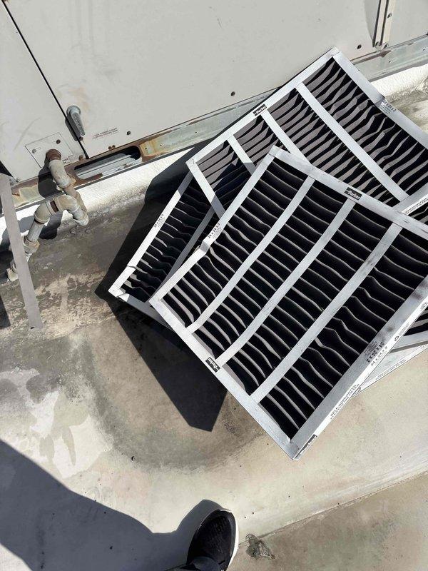 Completed scheduled commercial BFMA tune-up service on rooftop HVAC unit, which included replacement of nine air filters. Removed and installed new filters with white plastic frames, ensuring proper fit and airflow. Visual inspection confirmed system components were in working order following maintenance.