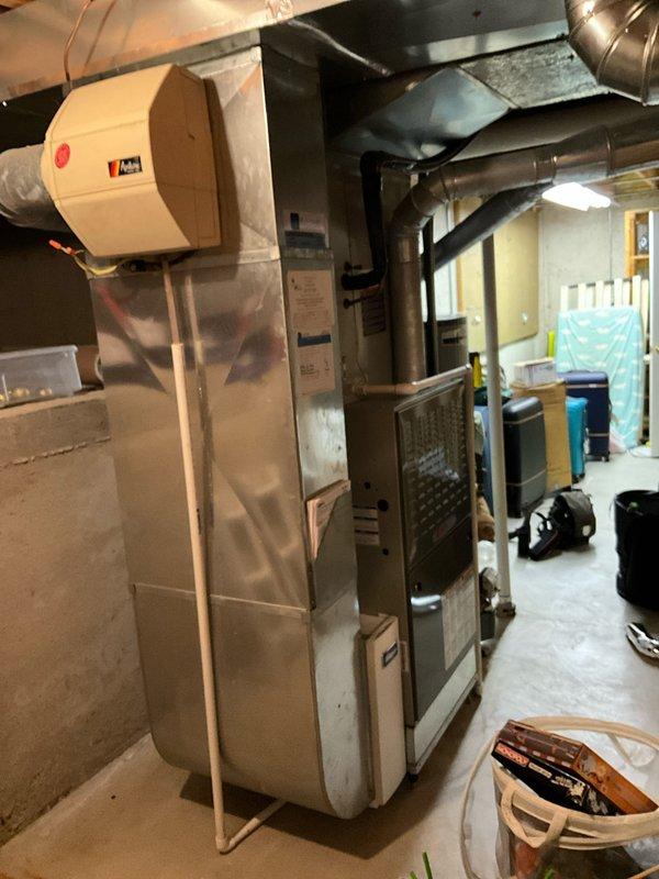 Conducted comprehensive assessment of 15-year-old residential HVAC system including furnace and air conditioning unit to evaluate condition and provide full system replacement estimate. Documented existing equipment configuration in basement mechanical room, including furnace with protective cardboard wrapping, A.O. Smith water heater, ACM humidifier unit, and associated ductwork and PVC piping. Photographed current system layout showing metallic ductwork connections, access panels, and mechanical components to support replacement proposal. Discussed system replacement options with homeowner and presented available promotional incentives and combination discounts for complete HVAC system installation.