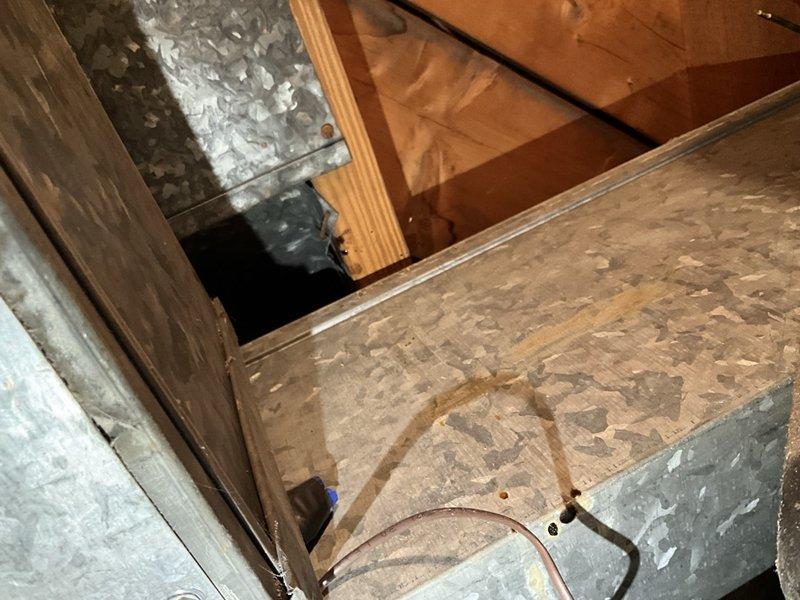 Responded to service call regarding overhead copper refrigerant line leak in furnace room that discharged oily residue onto surrounding surfaces. Upon inspection, observed evidence of refrigerant oil spray pattern on flooring, ductwork, and structural components beneath the copper line run. Documented existing conditions with photographs showing staining on plywood surfaces, copper refrigerant line routing through floor joists, and affected HVAC components. Based on visual assessment and client description of single occurrence event, leak appears to have self-sealed after releasing refrigerant charge from system. Recommended follow-up evaluation to identify leak source, pressure test system integrity, and determine if refrigerant recharge or line repair is required to restore proper operation.