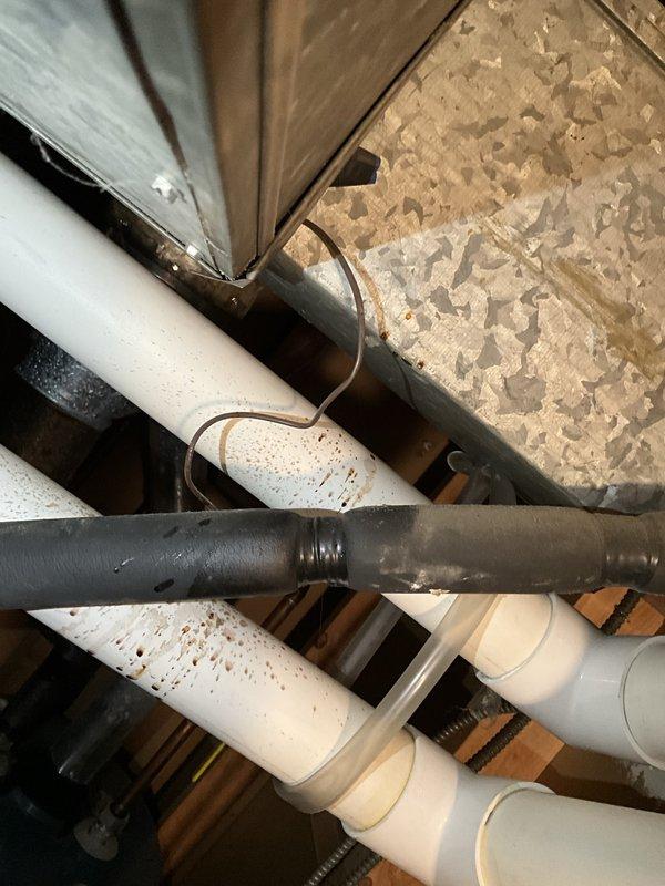 Responded to service call regarding overhead copper refrigerant line leak in furnace room that discharged oily residue onto surrounding surfaces. Upon inspection, observed evidence of refrigerant oil spray pattern on flooring, ductwork, and structural components beneath the copper line run. Documented existing conditions with photographs showing staining on plywood surfaces, copper refrigerant line routing through floor joists, and affected HVAC components. Based on visual assessment and client description of single occurrence event, leak appears to have self-sealed after releasing refrigerant charge from system. Recommended follow-up evaluation to identify leak source, pressure test system integrity, and determine if refrigerant recharge or line repair is required to restore proper operation.