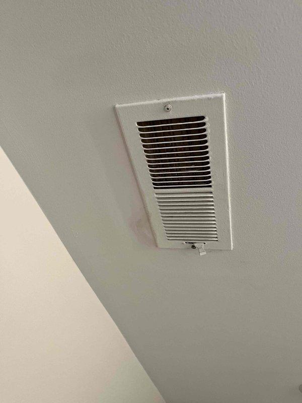 Completed callback service for register installation quality concerns. Cleaned all visible fingerprints and palm prints from register cover, secured mounting screw that was not fully tightened, and re-bent register louvers to ensure proper fit and flush mounting against ceiling surface. All adjustments verified and unit left in proper working condition.