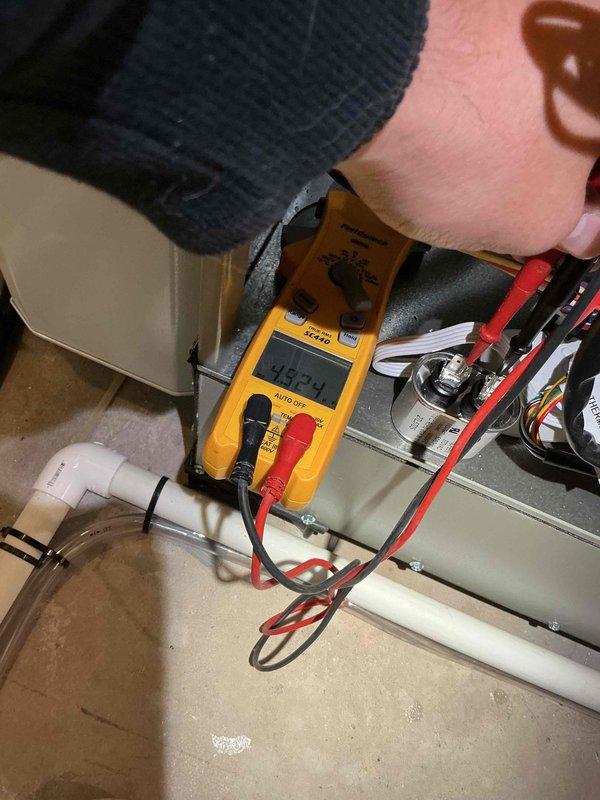 Completed comprehensive BFMA tune-up service on 5-month-old furnace and humidifier system in morning timeframe as requested. Performed full system diagnostics using digital multimeter to verify electrical readings and component functionality, measuring voltage at 146.24V during testing. Inspected furnace operation, checked all safety controls, verified proper airflow, and examined condensate drain lines with PVC piping secured appropriately. Evaluated portable dehumidifier unit positioned in unfinished basement area, confirming operational status with control panel indicators displaying proper function. All equipment found operating within manufacturer specifications with no issues identified during inspection.