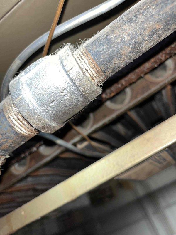 Responded to commercial gas odor complaint at facility with 20-year-old HVAC system. Upon arrival, conducted comprehensive gas leak detection survey of heating equipment and associated piping. Inspected aged gas supply lines showing significant corrosion and deterioration, with particular attention to threaded pipe connections and couplings. Identified compromised pipe joint with visible thread damage and material degradation at connection point. Evaluated furnace gas train components, including gas valve, manifold connections, and burner assembly. Examined ductwork connections and electrical controls in mechanical space. Documented condition of severely corroded gas piping requiring immediate attention due to safety concerns. Recommended complete gas line replacement and system evaluation given age of equipment and extent of deterioration observed throughout infrastructure.