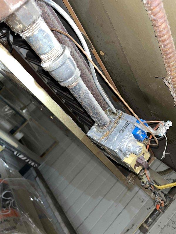 Responded to commercial gas odor complaint at facility with 20-year-old HVAC system. Upon arrival, conducted comprehensive gas leak detection survey of heating equipment and associated piping. Inspected aged gas supply lines showing significant corrosion and deterioration, with particular attention to threaded pipe connections and couplings. Identified compromised pipe joint with visible thread damage and material degradation at connection point. Evaluated furnace gas train components, including gas valve, manifold connections, and burner assembly. Examined ductwork connections and electrical controls in mechanical space. Documented condition of severely corroded gas piping requiring immediate attention due to safety concerns. Recommended complete gas line replacement and system evaluation given age of equipment and extent of deterioration observed throughout infrastructure.