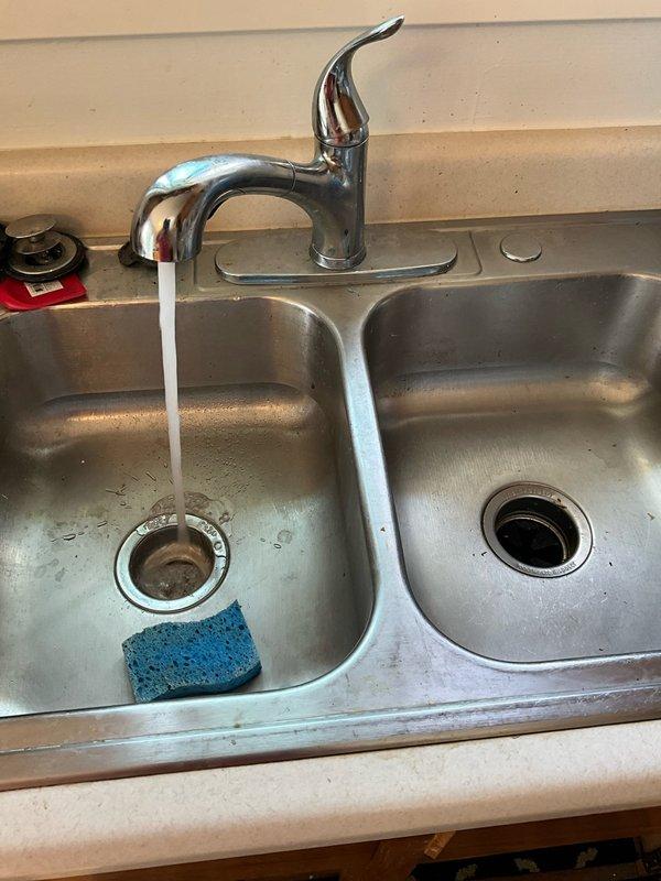 Responded to kitchen sink drainage issue affecting double-basin sink connected to garbage disposal unit. Upon inspection, accessed cabinet area beneath sink and assessed P-trap configuration and disposal connections. Cleared obstruction from drainage system, verified proper water flow through both basins and disposal unit, and tested all plumbing connections for leaks. System restored to full operational capacity with water draining freely through disposal and drain lines.